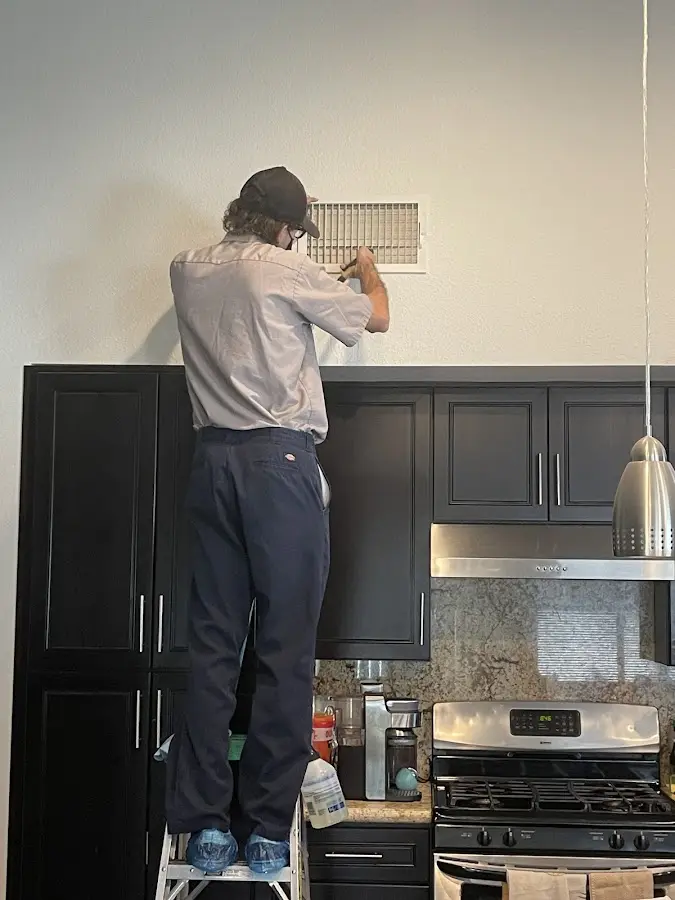 Technician inspecting an air vent during HVAC service in Vineland